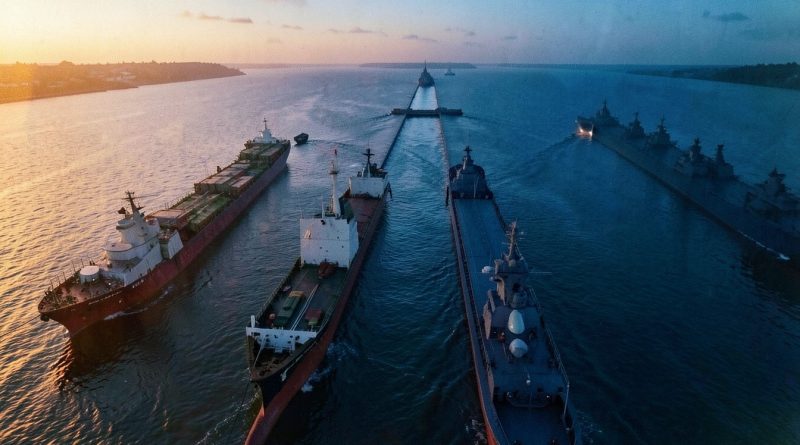 Estreito de Hormuz com navios ao entardecer, contraste entre luz dourada e azul